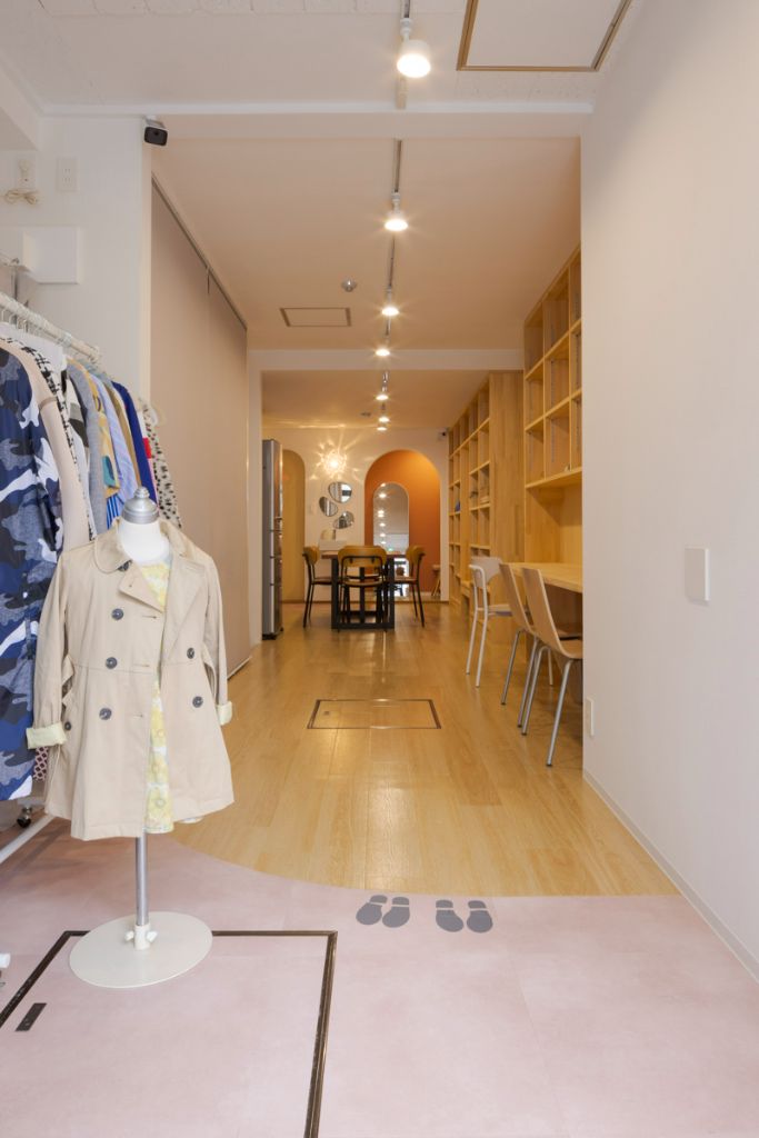 ほんとはね - 温かな空間の全体像、木製の棚とファッションラックがある明るい店内