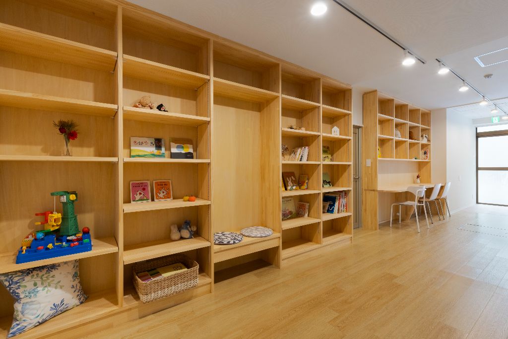棚貸し本屋エリア - 木製の棚にディスプレイされた本やおもちゃ、温かみのあるテーブルと椅子
